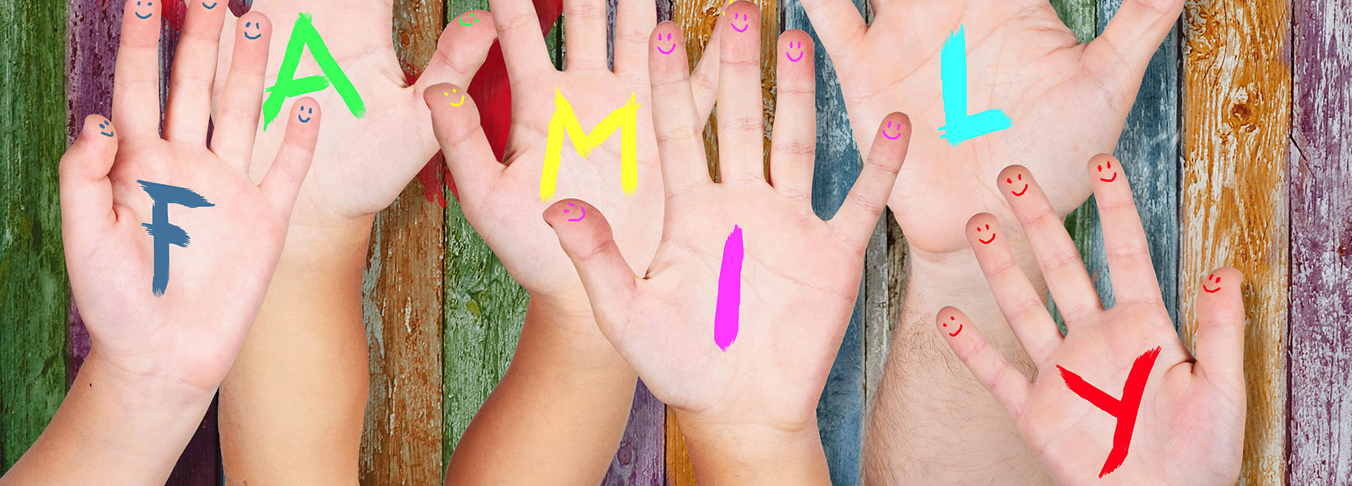 Mehrere Hände mit bunten Buchstaben bilden das Wort „FAMILY“, Finger mit Smiley-Gesichtern.