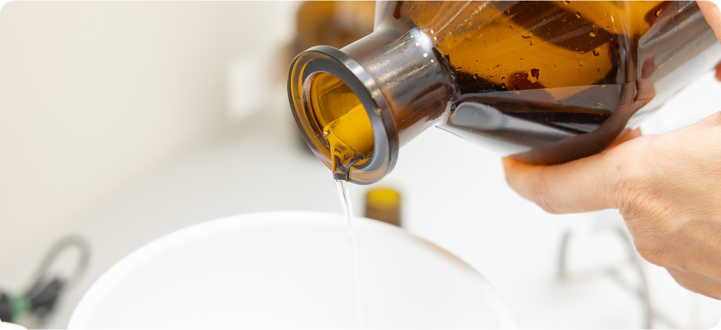 Klare Flüssigkeit wird aus einer braunen Apothekenflasche in ein Gefäß gegossen.